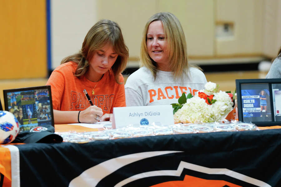 With her mother Kerry looking on, Ashlyn Digioia signs her soccer scholarship to the University of the Pacific during Johnson High School's Signing Day Wednesday morning. There were thirteen athletes signing their college scholarships.