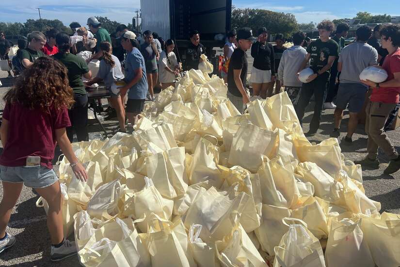 Students and employees gather around bags as Southwest ISD distributes turkeys.