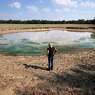 Gilda Jackson surveys an area that has dried, and dropped a few feet due to drought conditions affecting the region and her property in Paradise, Texas, Monday, Aug. 21, 2022. Many farmers, including Jackson, might see a benefit in the next 50 years from installing irrigation infrastructure. (AP Photo/Tony Gutierrez)