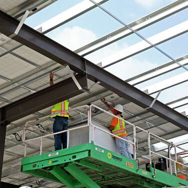Workers install another section of panels as Big Sun Solar owners Robert Muggins and Jason Pittman show off the solar panel arrangement installed at Rush Enterprises Truck Facility on May 6, 2020.