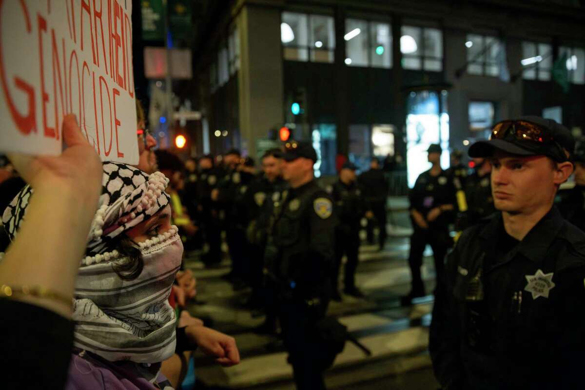 A protester holds sign in front of a police line during a march calling for a ceasefire of the ongoing Israel-Palestine conflict, as the 2023 Asia-Pacific Economic Cooperation Economic Leaders’ Week (APEC) is underway in San Francisco, Tuesday, Nov. 14, 2023.