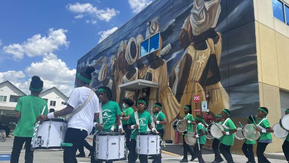 The Atherton Elementary School drumline delivers a performance on April 13, 2023, under the new recreation of John Biggers' 'The Stream Crosses The Path,' painted on the Julia C. Hester House wellness center at 2020 Solo St. in Houston, Texas, to celebrate the 80th anniversary of the community center's founding.