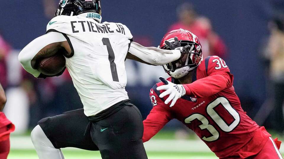 Jacksonville Jaguars running back Travis Etienne Jr. (1) pushes off the facemask of Houston Texans safety DeAndre Houston-Carson (30) as he runs for a first down during the second half of an NFL football game Sunday, Nov. 26, 2023, in Houston.