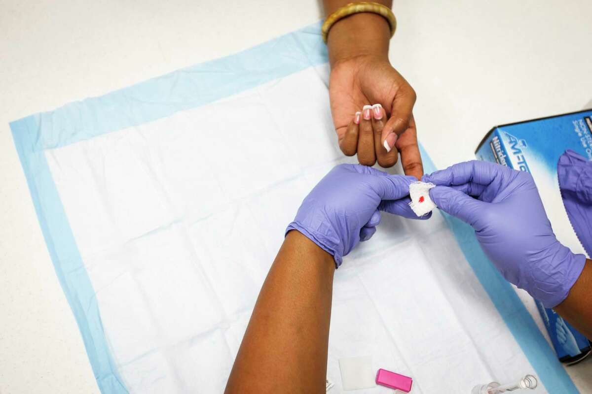 Timia Lott, left, has her finger pricked by Khalitha Russell, right, during a free HIV testing event at St. Luke Missionary Baptist Church, Sunday, July 8, 2012, in Humble. The NAACP, Bee Busy Wellness Center, and Rev. Timothy Sloan of St. Luke Missionary Baptist Church sponsored the 'Day of Unity' to mobilize faith leaders to talk about HIV/AIDS.