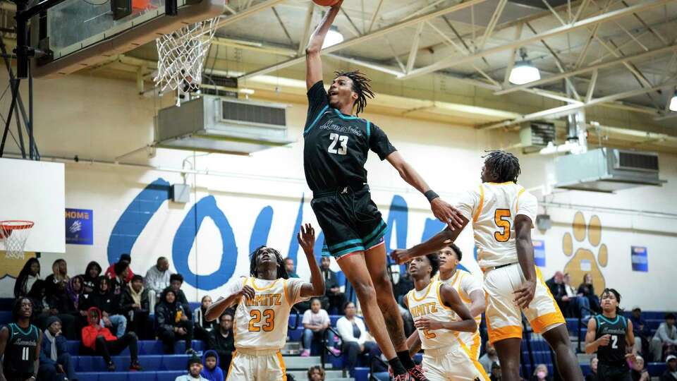 Pasadena Memorial center Robert Miller lll (23) goes up for a dunk over Nimitz High School's Jimiren Ratliff (23) and Malachai Augustus (5) during the first half of a non-district high school basketball game on Tuesday, Nov. 28, 2023 in Houston.