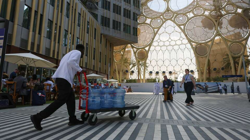 A worker transports a trolley of water containers through the Blue Zone past Al Wasl dome ahead of the COP28 climate conference at Expo City in Dubai, United Arab Emirates, on Wednesday, Nov. 29, 2023. More than 70,000 politicians, diplomats, campaigners, financiers and business leaders will fly to Dubai to talk about arresting the world's slide toward environmental catastrophe. Photographer: Hollie Adams/Bloomberg