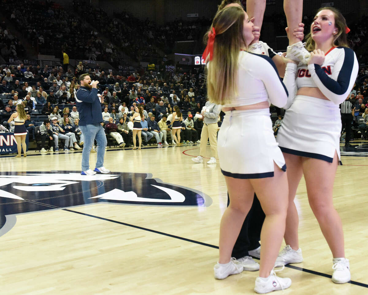 On-court host Conor Geary hypes up the Husky home crowd as cheerleaders perform a routine during UConn's men's basketball game at Gampel Pavilion in Storrs, Conn. Monday, Nov. 27, 2023.