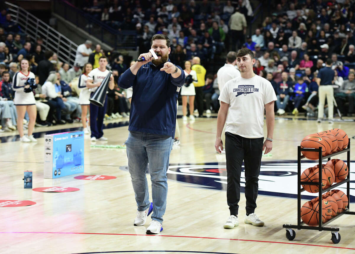 On-court host Conor Geary, left, introduces a student participating in a three-point shooting contest during UConn's men's basketball game at Gampel Pavilion in Storrs, Conn. Monday, Nov. 27, 2023.