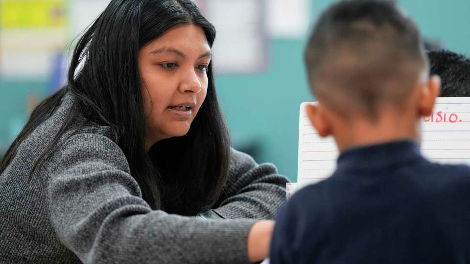 A dual language program pre-k teacher helps a student with his classwork on Monday, Nov. 27, 2023 at Gregg Elementary School in Houston.