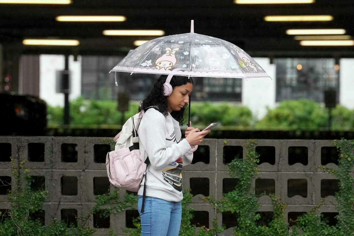 A pedestrians using umbrella on a rainy day while waiting for the bus on Thursday, Nov. 30, 2023 in Houston.