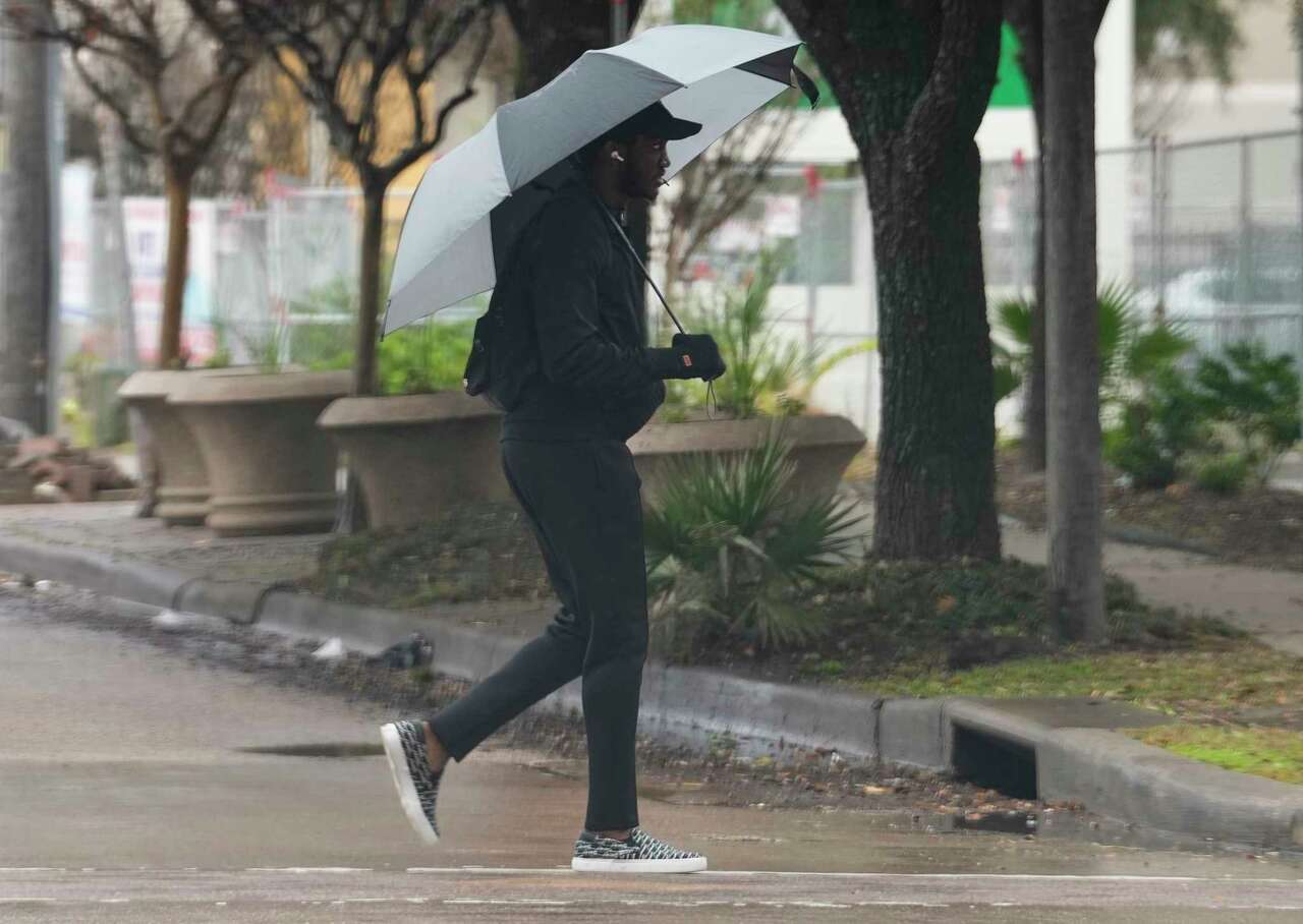 A pedestrians crossing Elgin Street on Main Street while using umbrella on a rainy day on Thursday, Nov. 30, 2023 in Houston.