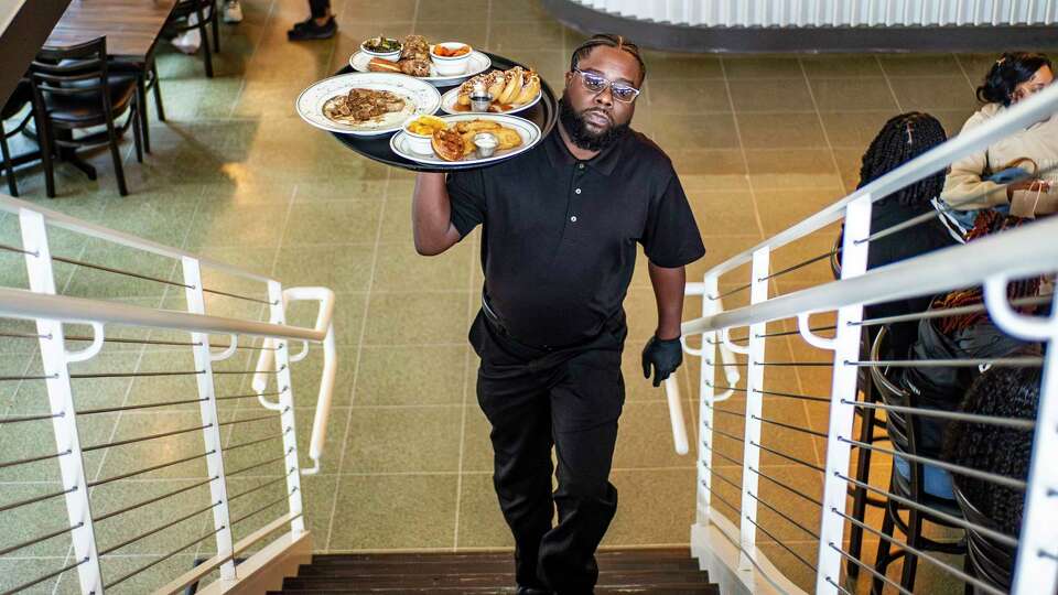 Server Leslie Haynes delivers entries to customers during the lunch rush, Friday, Dec. 1, 2023 at Taste Kitchen and Bar on Main Street in downtown Houston.