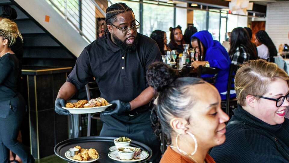 Erica Boone and Carolyn Griffith wait as server Leslie Haynes delivers entries during the lunch rush, Friday, Dec. 1, 2023 at Taste Kitchen and Bar on Main Street in downtown Houston.