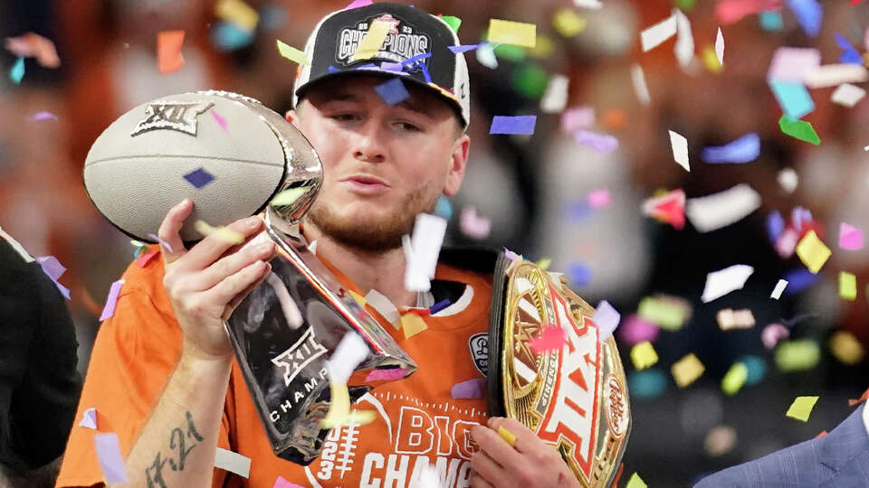 Texas quarterback Quinn Ewers blows a kiss to the trophy as he celebrates after the Big 12 Conference championship NCAA college football game against Oklahoma State in Arlington, Texas, Saturday, Dec. 2, 2023. (AP Photo/Tony Gutierrez)