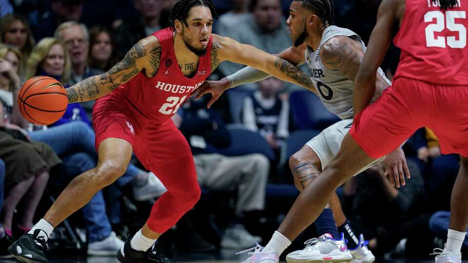 Houston guard Emanuel Sharp (21) drives against Xavier's Dayvion McKnight (20) during the first half of an NCAA college basketball game Friday, Dec. 1, 2023, in Cincinnati. (AP Photo/Jeff Dean)