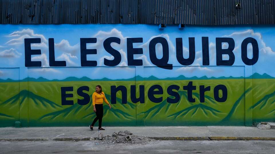 A pedestrian walks past a mural that reads 'The Essequibo Is Ours,' during a referendum vote in Caracas, Venezuela, on Sunday, Dec. 3, 2023. Following massive offshore oil discoveries in the region by Exxon Mobil Corp. and others, and with elections approaching, President Maduro is inflaming regional tension by reviving a long-dormant border dispute over the area known as the Essequibo. Photographer: Gaby Oraa/Bloomberg