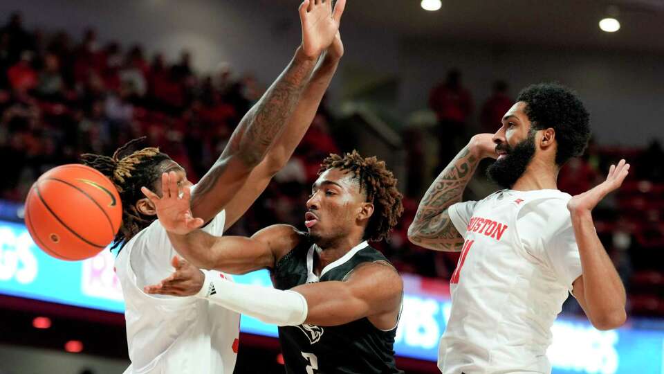 Rice Owls guard Mekhi Mason (2) passes between Houston Cougars forward Ja'Vier Francis (5) and guard Damian Dunn (11) during the first half of an NCAA college basketball game at the Fertitta Center, Wednesday, Dec. 6, 2023, in Houston.