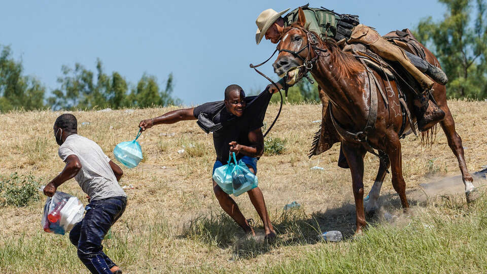 A 'challenge coin' circulating among U.S. Border Patrol agents and for sale on eBay depicts this scene, in which an agent on horseback tries to stop a Haitian migrant from entering an encampment on the banks of the Rio Grande in Del Rio, Texas, last September. (Paul Ratje/AFP/Getty Images/TNS)