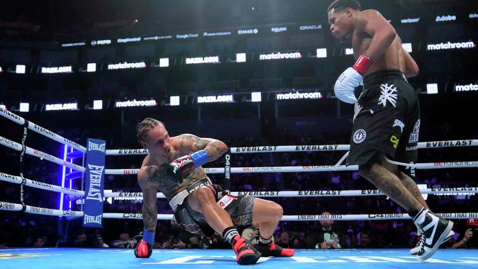 Regis Prograis, left, falls down next to Devin Haney during the WBC super lightweight title boxing bout Saturday, Dec. 9, 2023, in San Francisco. (AP Photo/Jeff Chiu)