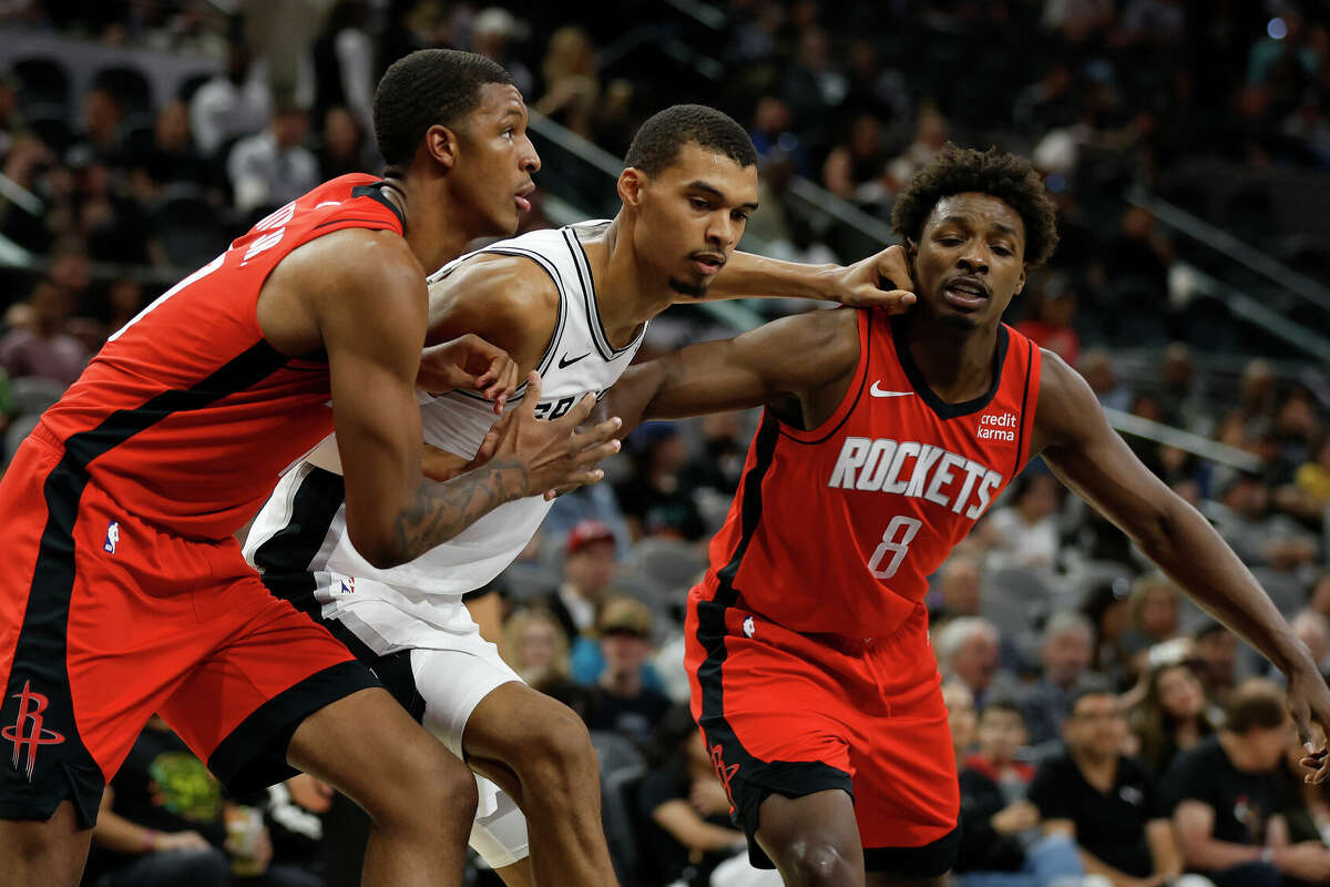 Victor Wembanyama #1 of the San Antonio Spurs battles for position against Jabari Smith #10 and Jae'Sean Tate #8 of the Houston Rockets in the first half of a pre-season NBA game at Frost Bank Center on October 16, 2023 in San Antonio, Texas. 