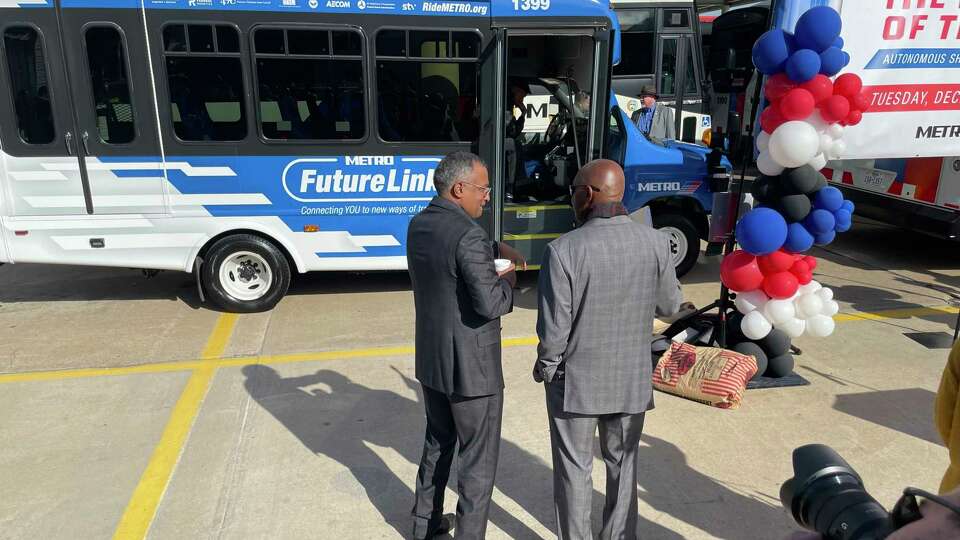 Metropolitan Transit Authority Chairman Sanjay Ramabhadran, left, and Houston Mayor Sylvester Turner discuss Metro's new autonomous shuttle at an unveiling on Dec. 12, 2023 at the transit agency's Kashmere Bus Operating Facility.