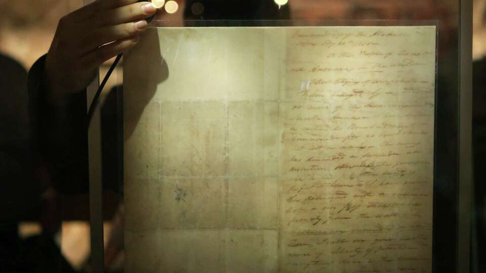 Daniel Alonzo, Archivist for the Texas General Land Office, takes a light temperature reading off a facsimile of the Travis Letter, which will be replaced with the original document, Feb. 23 - March 7, at the Alamo.