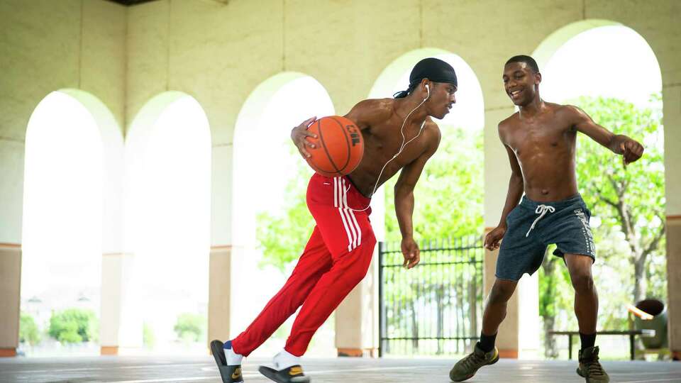Edward Brown, 17, is guarded by Kelvaughn Dorsey, 15, as they play basketball with friends at MacGregor Park, Wednesday, May 22, 2019. The teenagers had the day off from Northside High School, and they came to the park to play basketball on the shaded court.