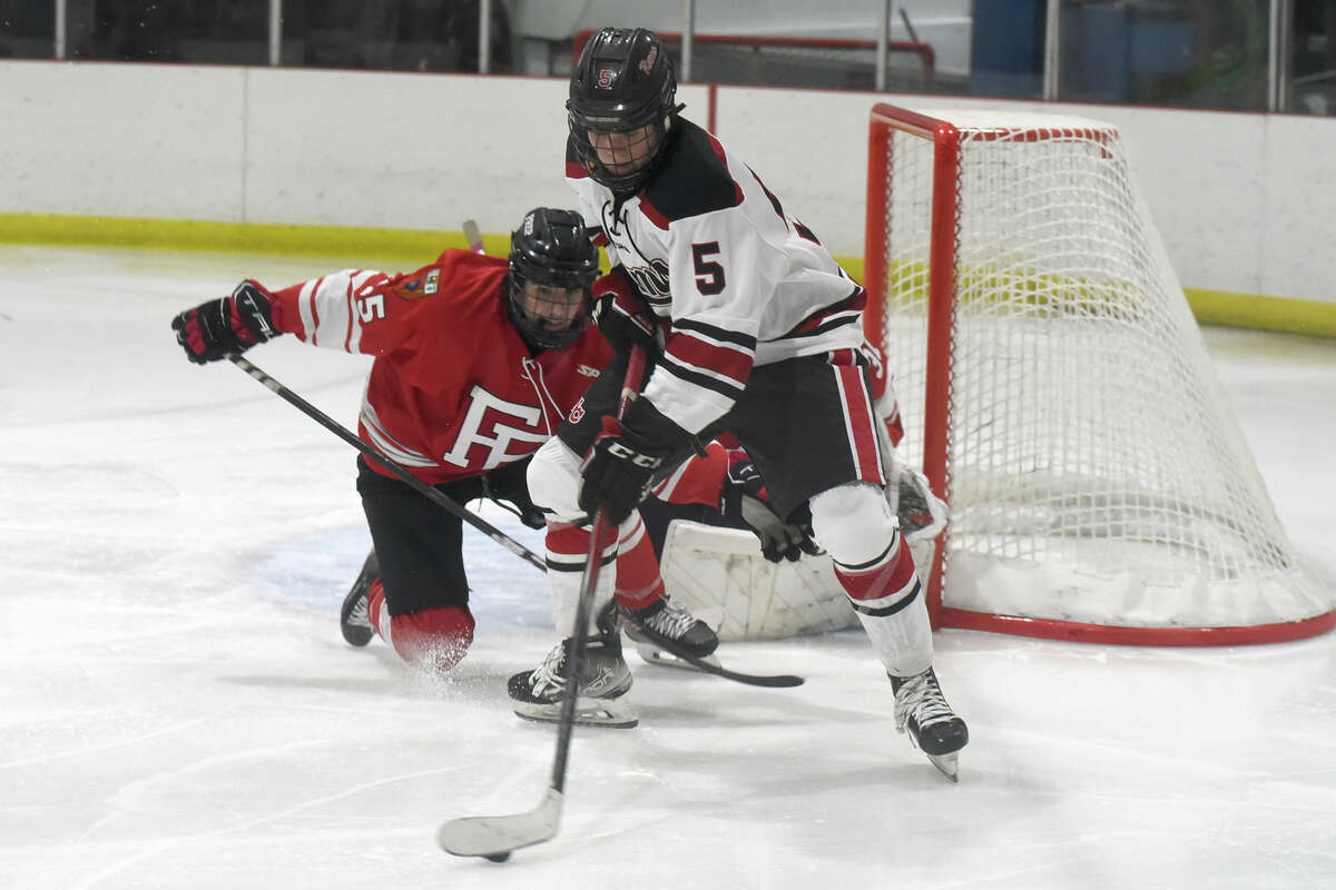New Canaan's Braydon Robie (5) looks for a shot while Fairfield Prep's Gavin Burke (15) defends during a boys ice hockey game at the Darien Ice House on Friday, Dec. 15, 2023.