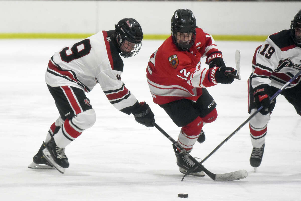 Fairfield Prep's James Murphy (12) battles New Canaan's Max Lowe (9) and Anthony DelCarmine (19) during a boys ice hockey game at the Darien Ice House on Friday, Dec. 15, 2023.