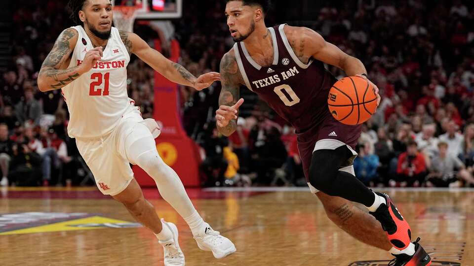 Texas A&M guard Jace Carter (0) drives around Houston guard Emanuel Sharp (21) during the first half of an NCAA college basketball game, Saturday, Dec. 16, 2023, in Houston. (AP Photo/Kevin M. Cox)