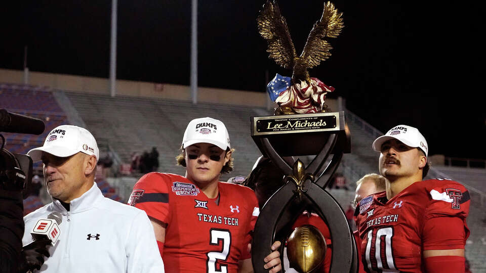 Texas Tech coach Joey McGuire, left, is interviewed while quarterback Behren Morton (2) and linebacker Jacob Rodriguez (10) hold the trophy after the team's win over California in the Independence Bowl NCAA college football game Saturday, Dec. 16, 2023, in Shreveport, La. (AP Photo/Rogelio V. Solis)