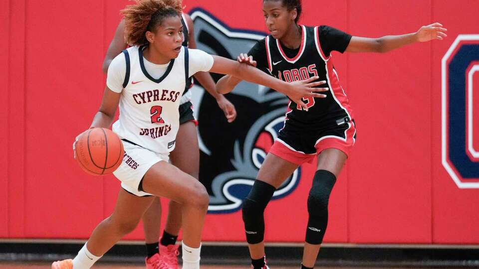 Cypress Springs shooting guard Ayla McDowell (2) drives the ball against Langham Creek shooting guard Jade Prevost (13) during the first half of a District 16-6A high school basketball game at Cypress Springs High School, Tuesday, Dec. 19, 2023, in Cypress.