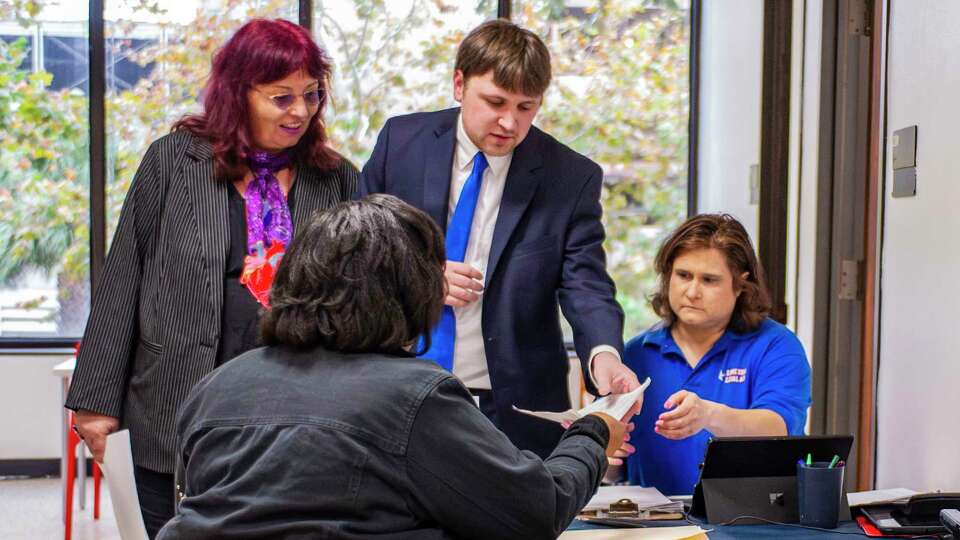 Harris County Precinct 1, Place 2 Eviction Diversion Facilitator, Loreta Kovacic, observes as Lone Star Legal Aid attorney Benjamin Daily and Intake Supervisor Deanna Sline, provide legal assistance to a visitor outside the court Wednesday, Dec. 20, 2023.