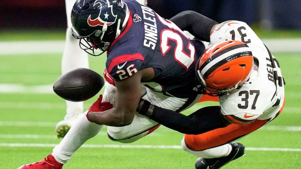 Houston Texans running back Devin Singletary (26) loses the handle on the ball as he is hit by Cleveland Browns safety D'Anthony Bell (37) during the first half of an NFL football game Sunday, Dec. 24, 2023, in Houston. He recovered his own fumble.