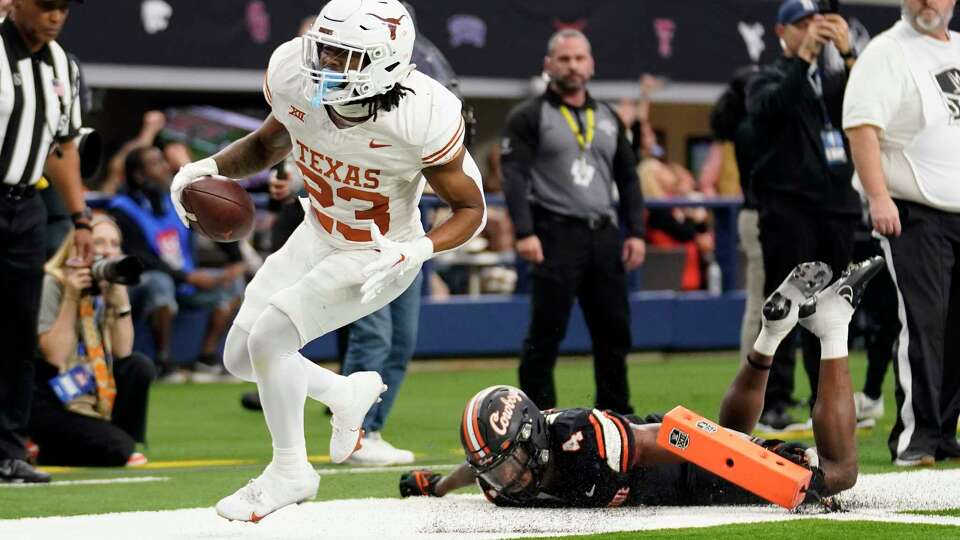 CORRECTS TO TEXAS RUNNING BACK JAYDON BLUE (23) NOT DEFENSIVE BACK JAHDAE BARRON - Texas running back Jaydon Blue (23) gets past Oklahoma State linebacker Nickolas Martin (4) and into the end zone to score a touchdown on a running play in the first half of the Big 12 Conference championship NCAA college football game in Arlington, Texas, Saturday, Dec. 2, 2023. (AP Photo/Tony Gutierrez)