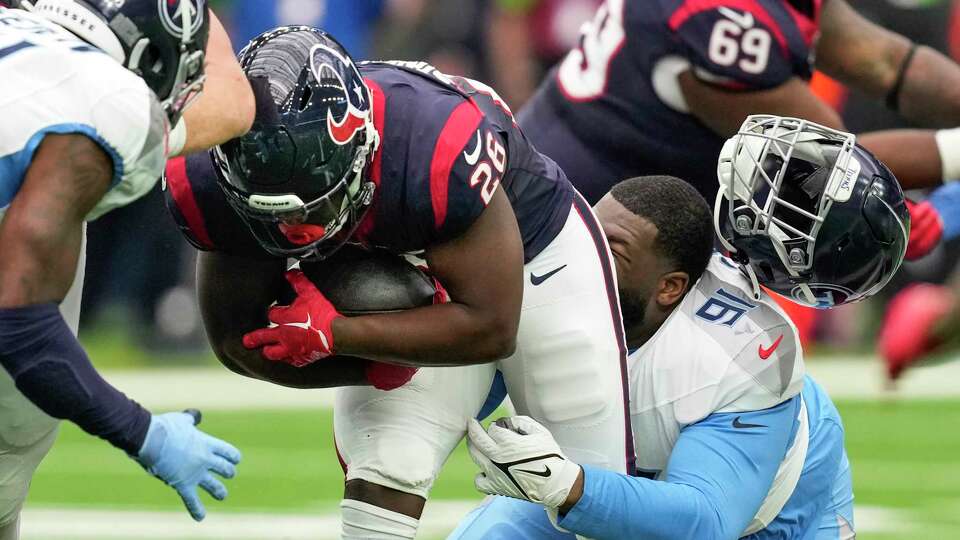 Tennessee Titans defensive tackle Keondre Coburn (91) loses his helmet as he tackles Houston Texans running back Devin Singletary (26) during the first half of an NFL football game Sunday, Dec. 31, 2023, in Houston.