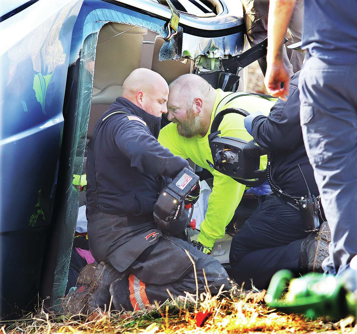 Firefighters work to free the driver after removing the windshield and roof of the vehicle Tuesday.