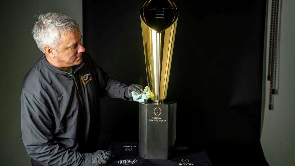 Charley Green, CFP Trophy manager, polishes the College Football Playoff National Championship trophy as he prepares it to be photographed in the Chronicle Studio on Thursday, Jan. 4, 2024 in Houston.