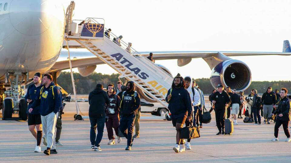 Michigan players, coaches, and family members unload from the plane after it lands at George Bush Intercontinental Airport as the team arrives in Houston, Friday, Jan. 5 ,2023 for the 2024 College Football Playoff National Championship.