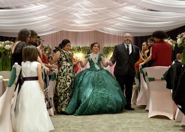 Sienna Raley, flanked by her parents Maria and Troy, begins the Grand Entrance at her quinceañera Saturday, Dec. 16, in Diboll. 