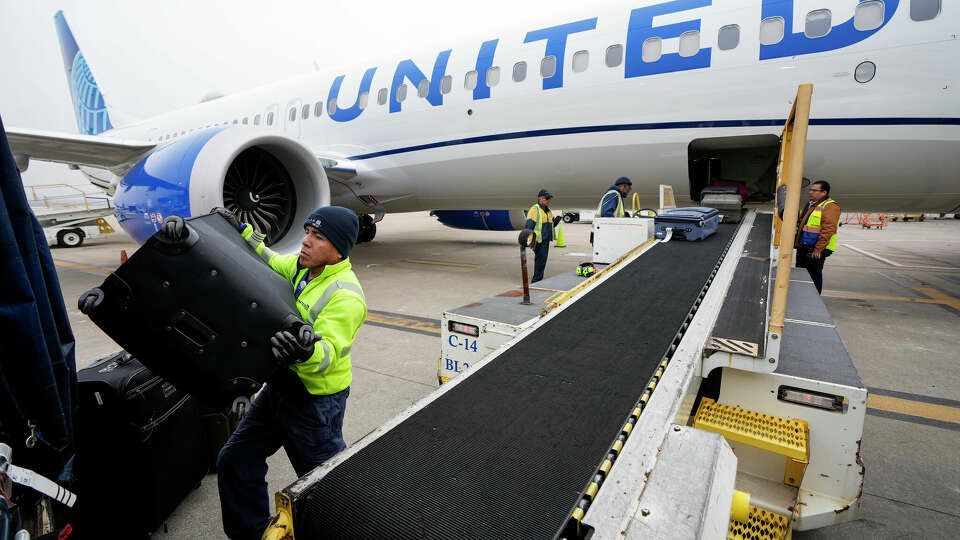 Juan Chavez handles baggage as is comes off an aircraft upon landing at George Bush Intercontinental Airport on Thursday, Dec. 21, 2023, in Houston. Passengers may see delays or cancellations because of severe winter weather and the grounding of Boeing 737 Max 9 planes in the second week of January.