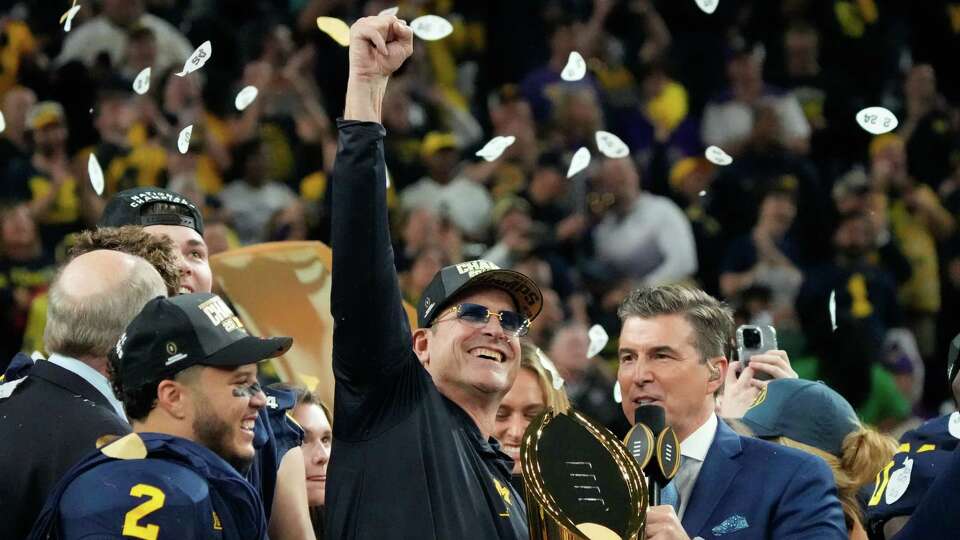 Michigan Wolverines head coach Jim Harbaugh holds up the championship trophy after defeating Washington 34-13 during the national championship NCAA College Football Playoff game at NRG Stadium, Monday, Jan. 8, 2024, in Houston.