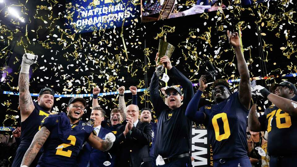 Michigan Wolverines head coach Jim Harbaugh raises the championship trophy after defeating Washington 34-13 during the national championship NCAA College Football Playoff game at NRG Stadium, Monday, Jan. 8, 2024, in Houston.