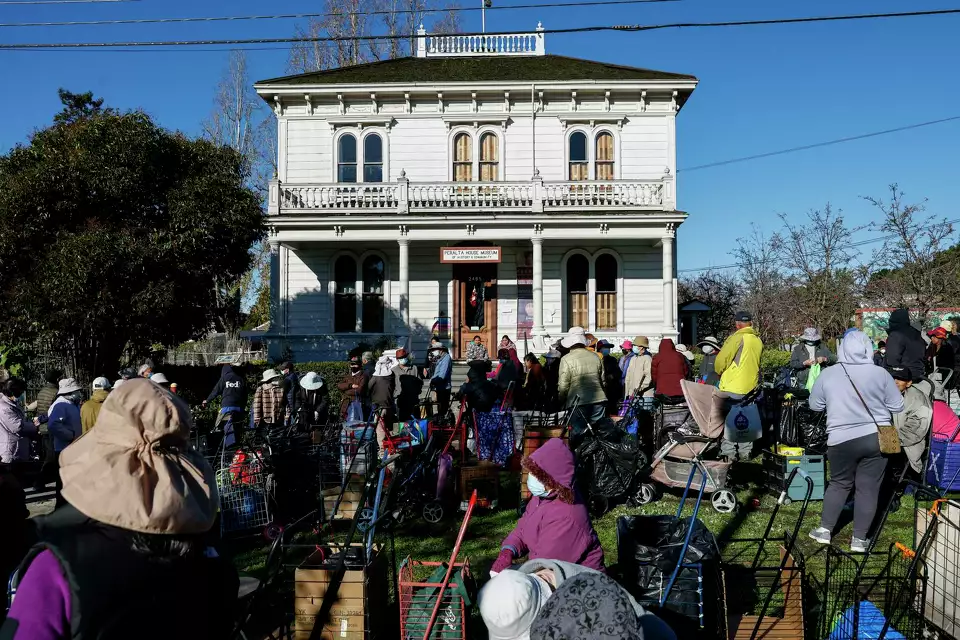 A crowd of people with carts waiting outside a building