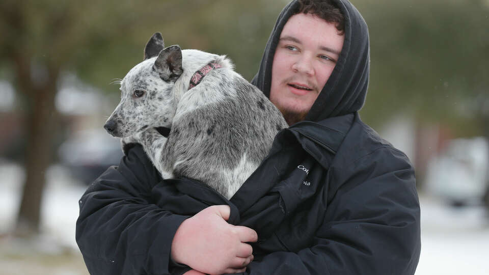 Levi Johnson carries his dog, Dally, down the street as they head back to their house after snow and ice covered the Houston metro area on Feb. 15, 2021, in Kingwood. 