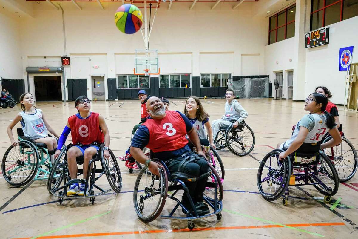 Coach and employee Victor Ventura laughs with the kids during wheelchair basketball practice at the West Gray Multi-Service Center, on Tuesday, Jan. 9, 2024, in Houston.