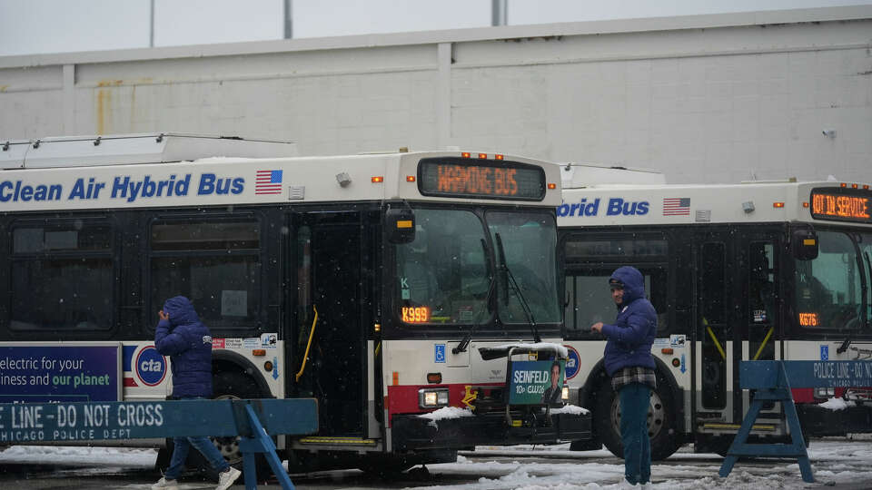 Snow falls as migrants continue to be housed by the city in 'warming' buses in the 800 block of South Desplaines Street during a winter storm Friday, Jan. 12, 2024, in Chicago. (AP Photo/Erin Hooley)