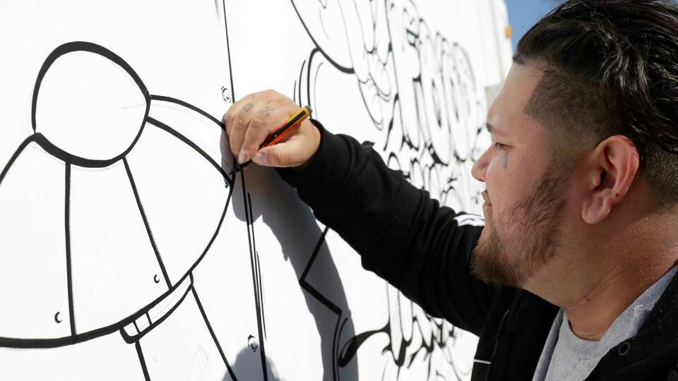 Artist Dreamz, from Rosenberg, TX, uses markers as he applies his freestyle artwork to the exterior of a food trailer outside the location of the new 2D style restaurant Foodaholic HTX Saturday, Jan. 13, 2024 in Splendora, TX.