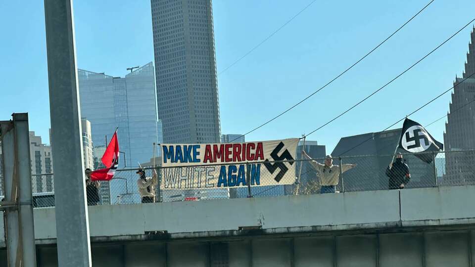 A group of demonstrators holding Nazi flags and a banner on a bridge above Interstate 45 in Houston, Saturday Jan. 13, 2023.