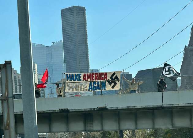 A group of demonstrators holding Nazi flags and a banner on a bridge above Interstate 45 in Houston, Saturday Jan. 13, 2023.